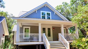 A two-story house with a covered porch, a front door, and a staircase leading to the upper level.