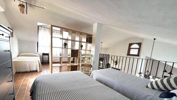 A bedroom with two beds, a chair, a bookshelf, and a staircase. - Villa Florida 745 in Conil de la Frontera (Conil de la Frontera)