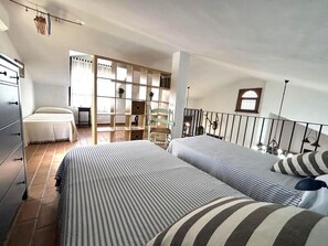 Ein Schlafzimmer mit zwei Betten, einem Sessel, einem Bücherregal und einer Treppe.