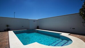 A rectangular swimming pool with a curved edge, surrounded by a white wall and a tiled patio. - Villa Florida 745 in Conil de la Frontera (Conil de la Frontera)