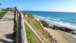 A coastal walkway with a wooden fence, a sandy beach, and ocean waves. - Suite Las Adelfas in Conil de la Frontera (Conil de la Frontera)