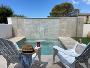 A poolside area with two white lounge chairs, a straw hat, and a can of Corona beer on a small table. - Suite La Buganvilla in Conil de la Frontera (Conil de la Frontera)