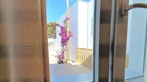 Vista a través de una ventana con un poste de madera y una planta floreciente de color rosa afuera.