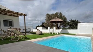 A swimming pool with a pergola, outdoor seating, and a thatched umbrella. - Suite La Morera in Conil de la Frontera (Conil de la Frontera)