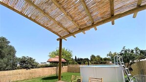A wooden deck with a table and chairs, a hot tub, and a covered area with a thatched roof. - Suite La Morera in Conil de la Frontera (Conil de la Frontera)