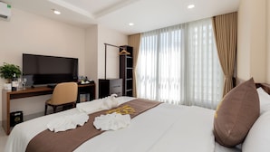 A hotel room with a bed, a desk with a TV, a chair, and a wardrobe.