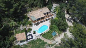Vista aérea de una amplia casa moderna con piscina, rodeada de un bosque denso.