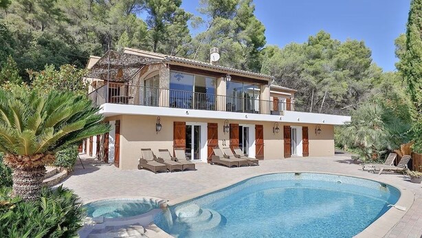 Casa de dos pisos con piscina, rodeada de árboles y con mobiliario para exteriores.