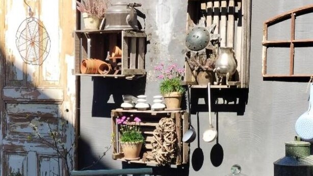 A rustic outdoor seating area with a round metal table, a bench, and various potted plants. - Vacation apartment Am Schloßberg (Solingen)