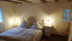 A bedroom with a bed, bedside tables, a nightstand, a window, and a chair. - Vacation apartment Am Schloßberg (Solingen)
