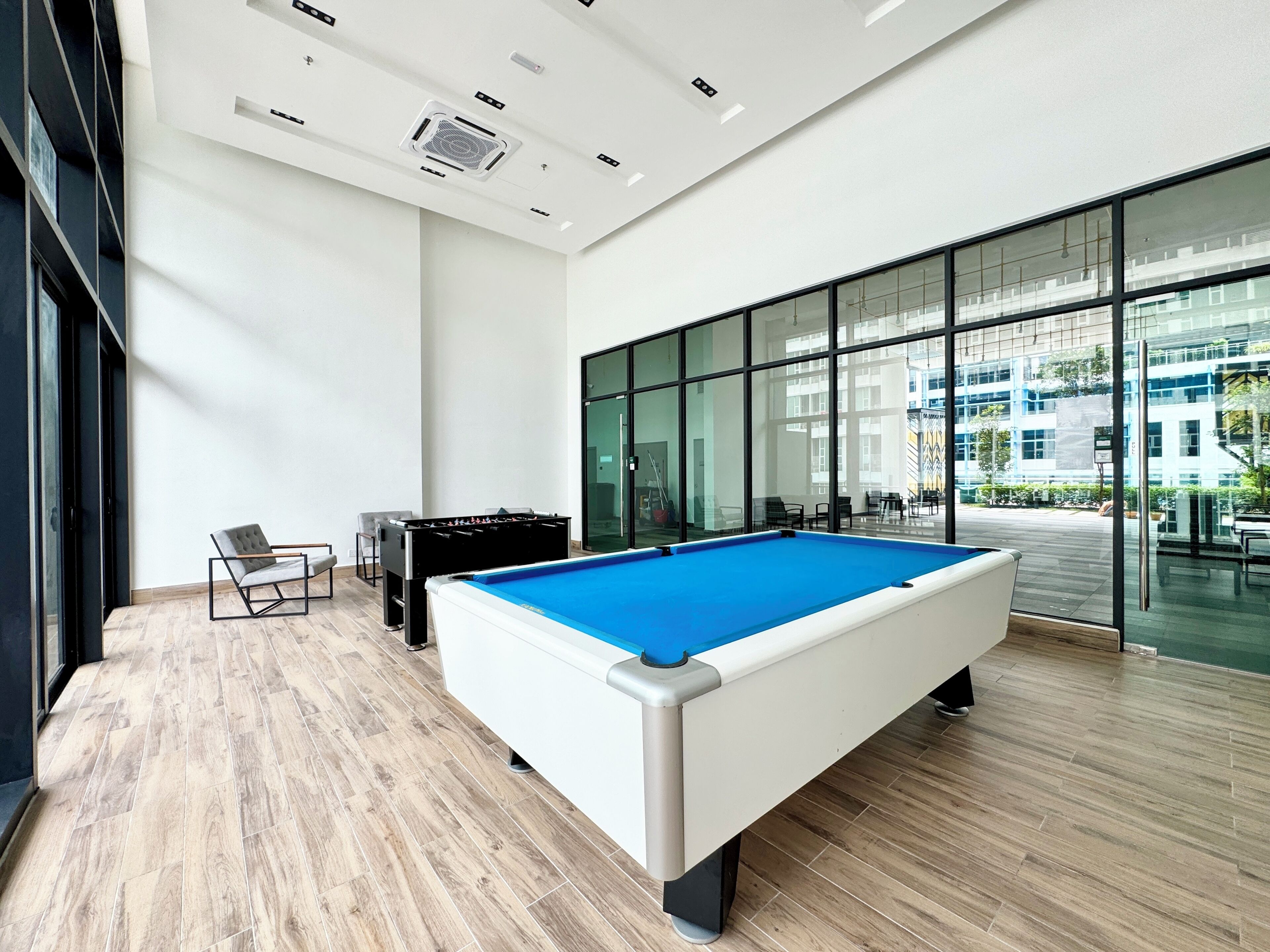 A pool table in a modern indoor space with a view of a building outside.
