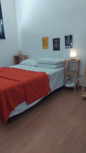 Une chambre à coucher comprenant un lit, une table de chevet, une lampe et deux éléments de décoration murale.