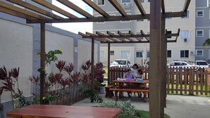 An outdoor patio area with wooden tables and benches, surrounded by a wooden pergola structure. - Apartment 600 meters from the beach (Ponta de Campina Cabedelo)