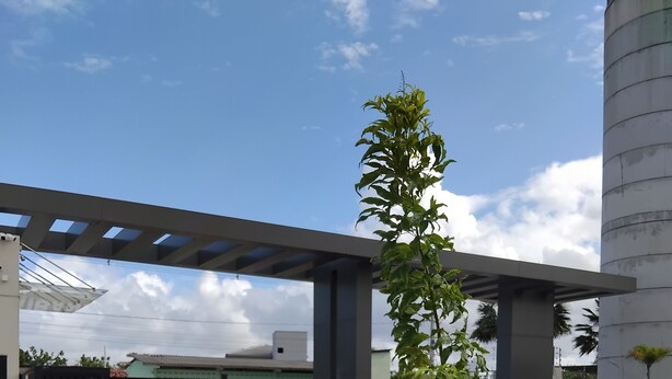 A gated entrance with a pedestrian crossing, a covered walkway, and a large cylindrical structure in the background. - Apartment 600 meters from the beach (Ponta de Campina Cabedelo)