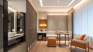 A modern hotel room with a large mirror, a sofa, a small table, and a wooden floor. - World Hotel (Jinan CBD Dingjiazhuang Subway Station) (Jinan)