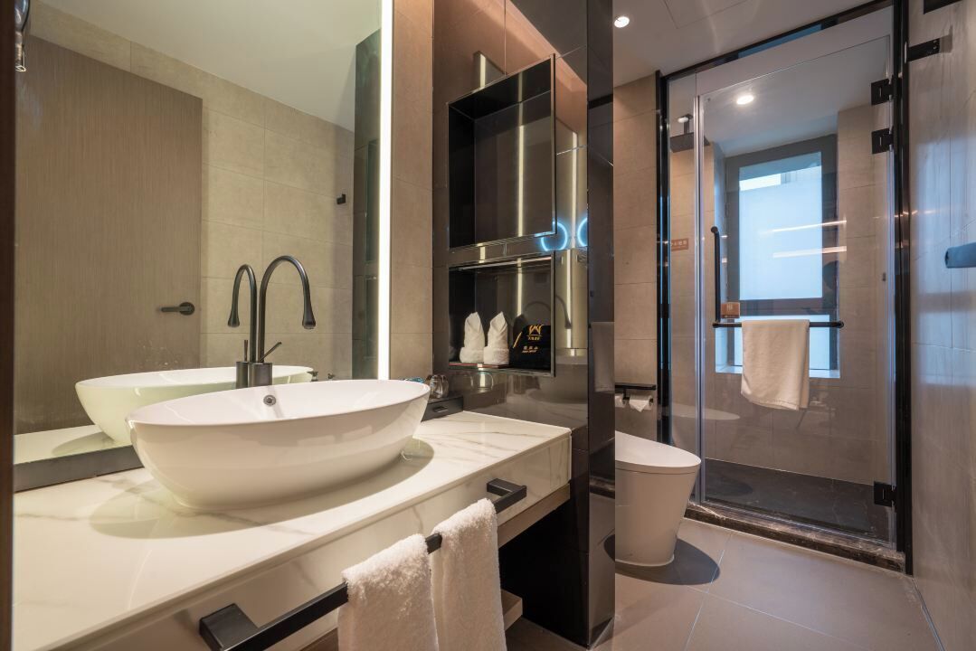 A modern bathroom with a large white sink, a glass shower enclosure, and a mirror above the sink.
