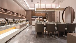 A modern dining area with a long counter, multiple chairs, and a central table. - World Hotel (Jinan CBD Dingjiazhuang Subway Station) (Jinan)