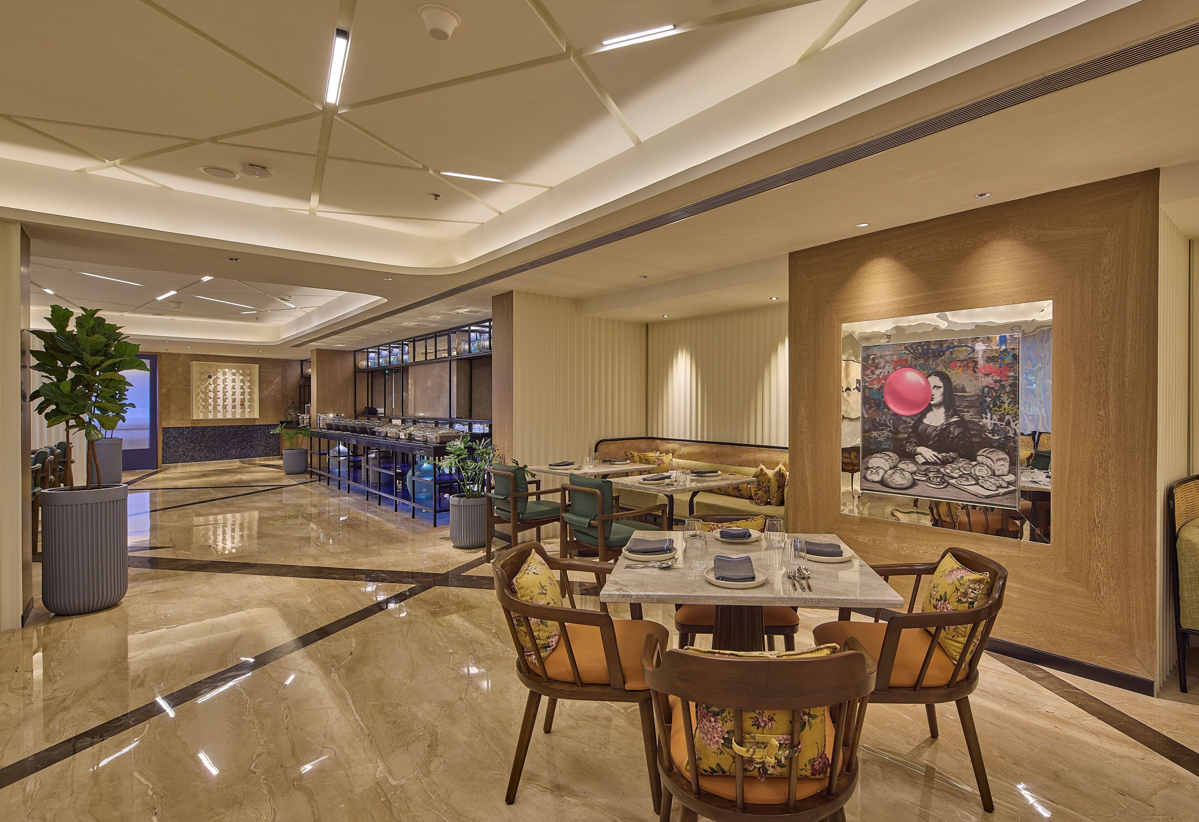 A spacious hotel lobby with a marble floor, seating areas, and a large painting on the wall.