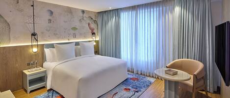 Une chambre d’hôtel moderne, dotée d’un grand lit, d’une table de chevet, d’une chaise et d’un téléviseur.