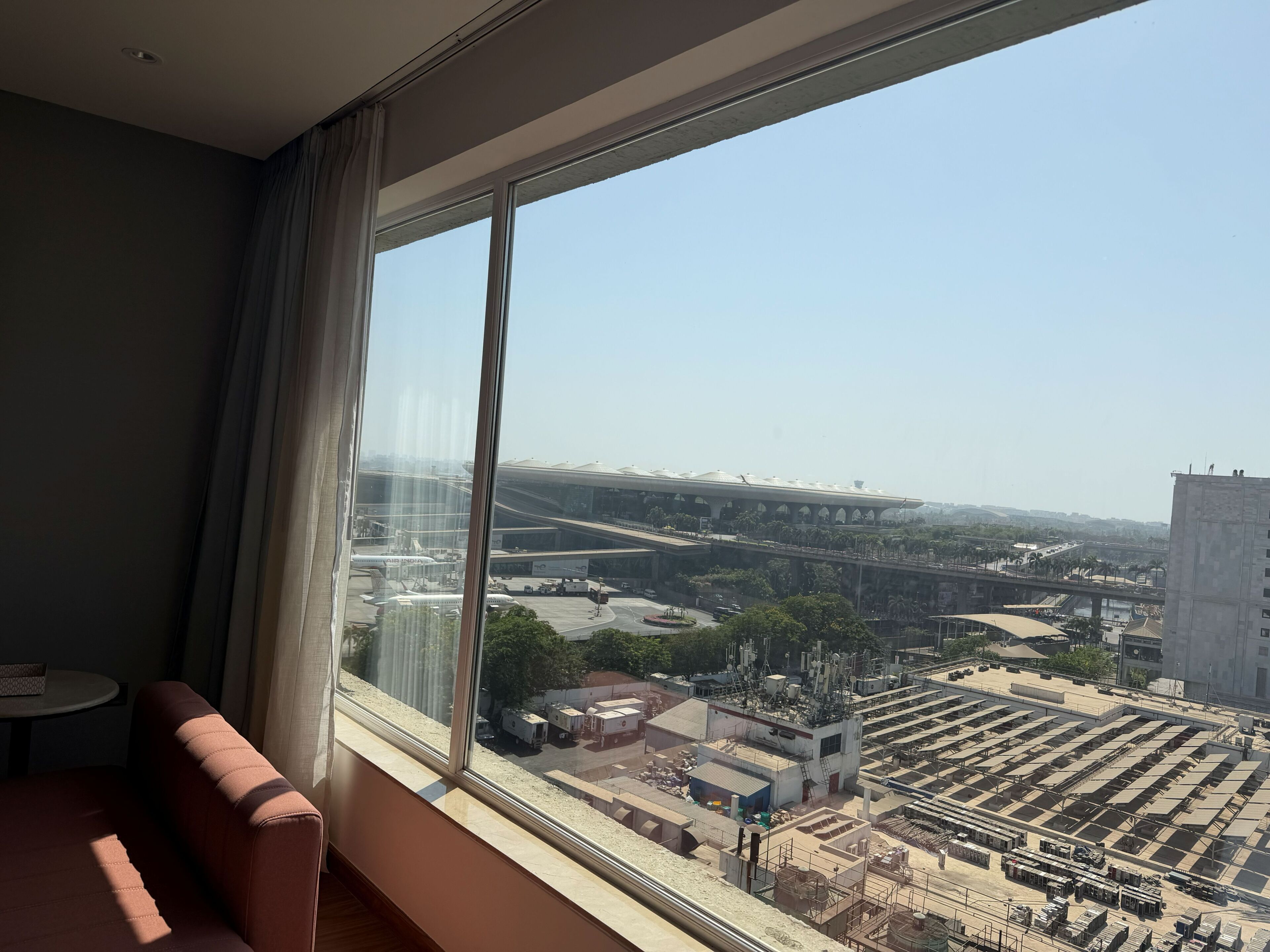 A room with a large window overlooking an airport and a cityscape.
