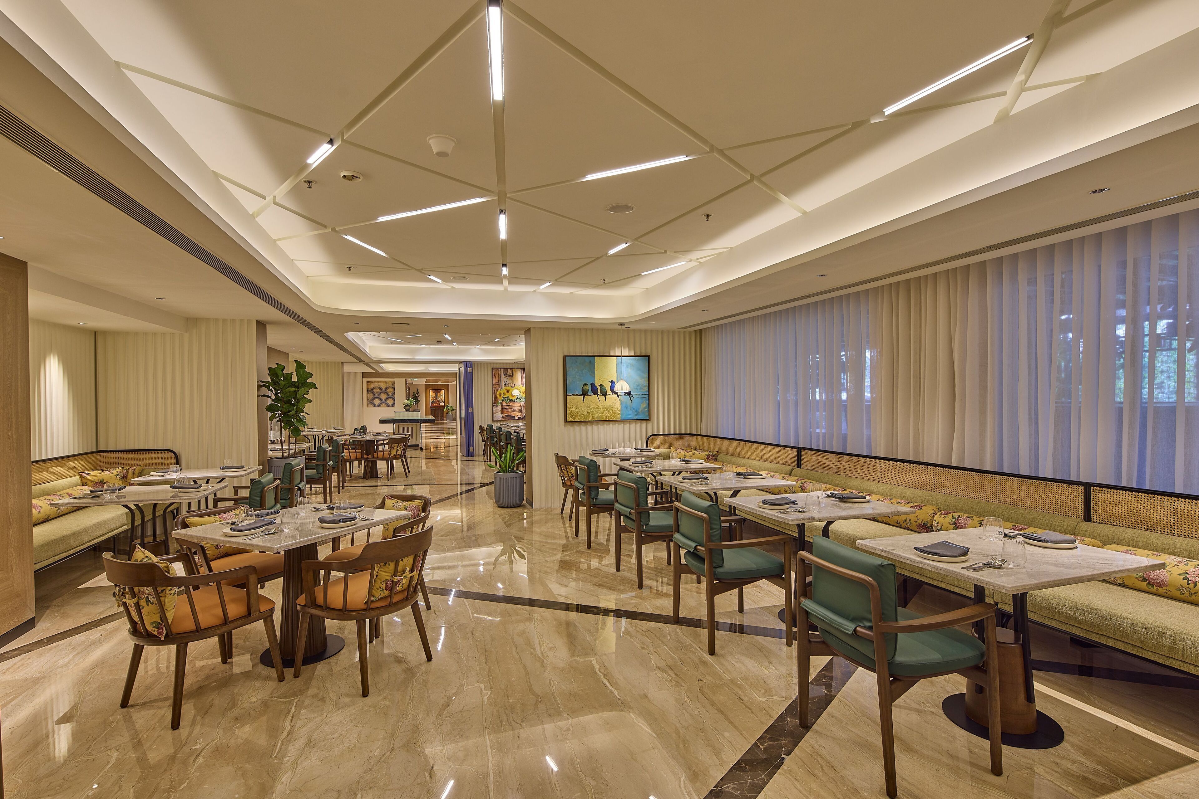 A spacious hotel lobby with a mix of seating areas, including a long bench and multiple tables.