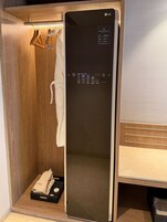 A modern, compact bathroom with a wooden vanity, a built-in mirror, and a towel rack.