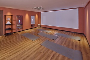 A room with wooden flooring, a projection screen, and yoga mats.