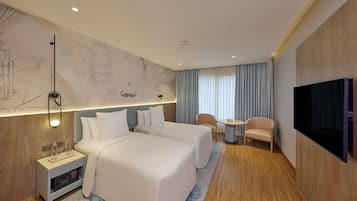 Een hotelkamer met twee bedden, een televisie, een bureau en een stoel.