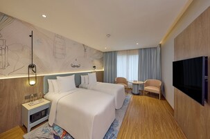 Een hotelkamer met twee bedden, een televisie, een bureau en een stoel.