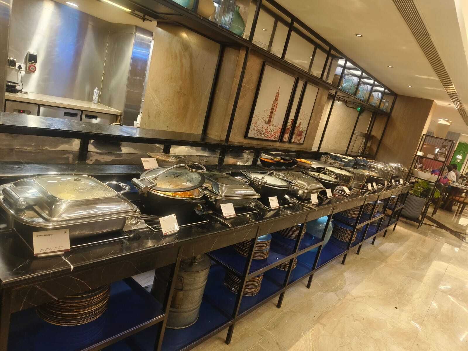A buffet setup with multiple serving stations, each with covered dishes and serving utensils.