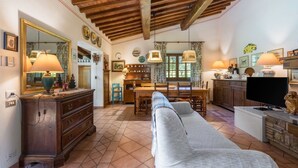 A cozy living room with a sofa, wooden furniture, a TV, and a dining area with a table and chairs. - Grace Home, Pool, Wifi, Gambassi Terme (Gambassi Terme)