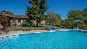 A swimming pool with lounge chairs, a stone building, and a large tree in the background. - Grace Home, Pool, Wifi, Gambassi Terme (Gambassi Terme)