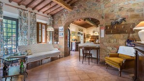 A rustic interior with a stone wall, wooden beams, a sofa, a table, and a chair. - Grace Home, Pool, Wifi, Gambassi Terme (Gambassi Terme)