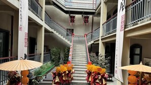 A multi-level atrium with a central staircase, surrounded by tables with floral arrangements and umbrellas.
