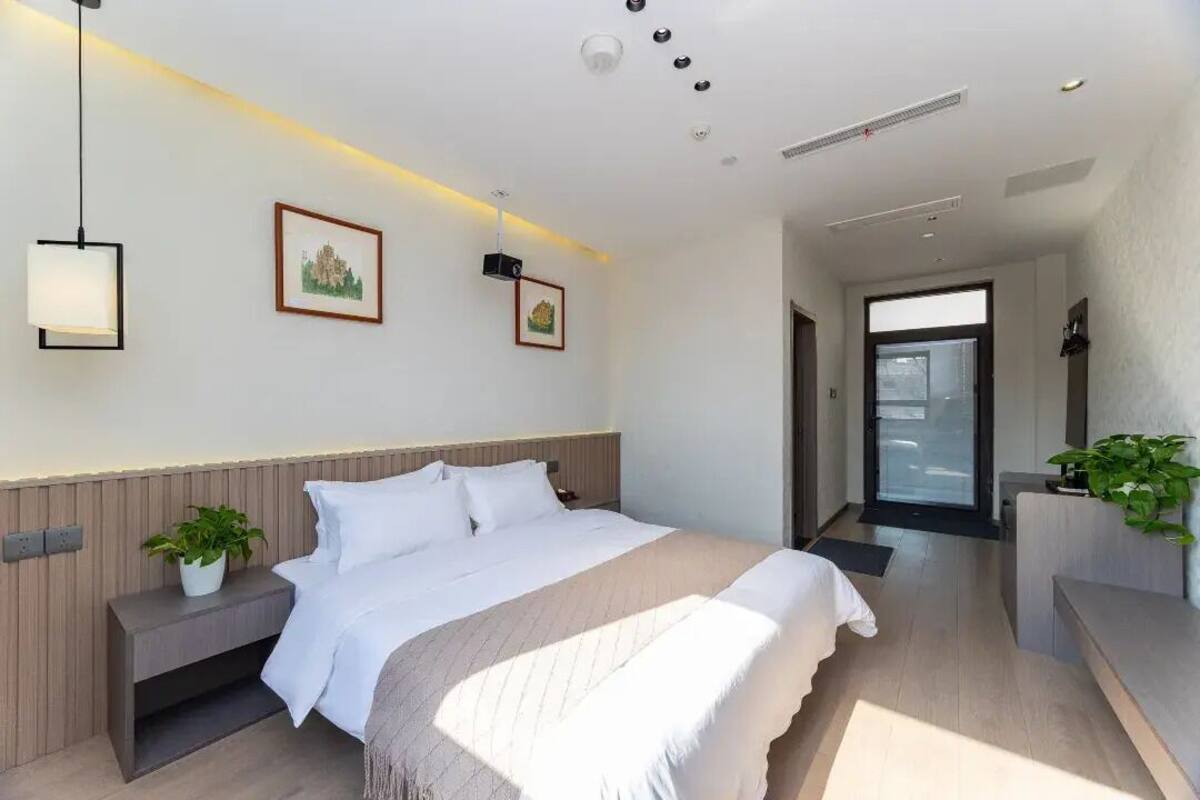 Una habitación de hotel moderna con una cama grande, mesitas de noche y una planta en maceta.