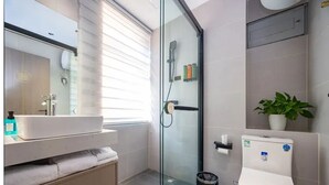 A modern bathroom with a glass shower enclosure, a white sink, and a toilet.
