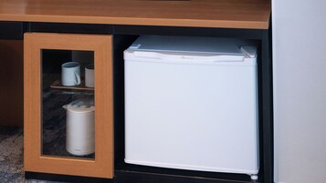 A compact refrigerator with a built-in freezer compartment, placed under a wooden cabinet with a glass door.
