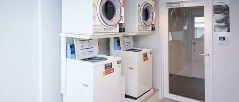 A laundry area with two stacked washing machines and a door leading to a utility room.