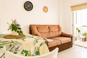 A living room with a sofa, a clock, a decorative plate, and a table with a plant. - Modern Studio with Pool, Puerto de La Cruz (Puerto de la Cruz)