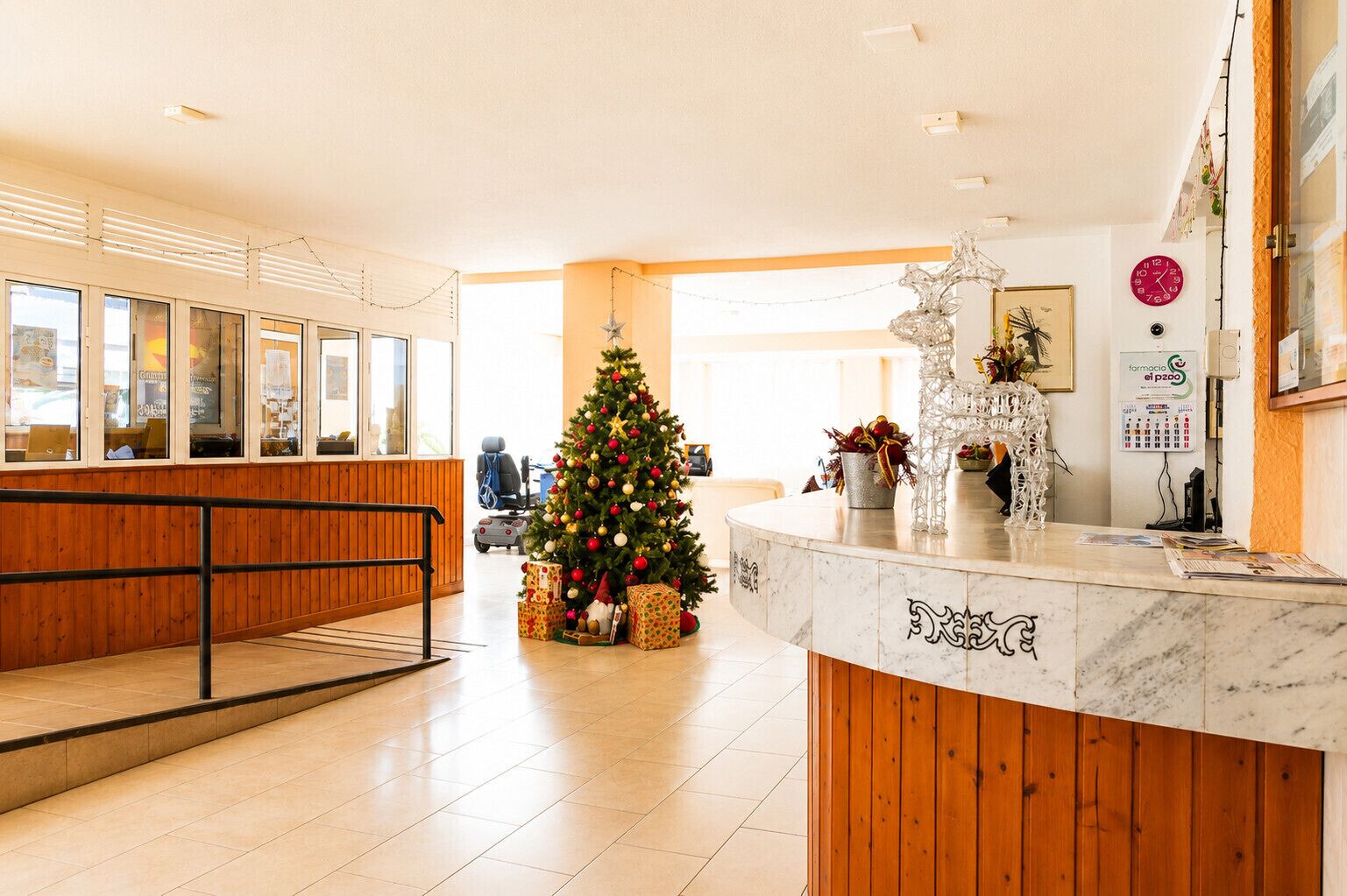 Zona de recepción con un árbol de Navidad, mostrador de mármol y rampa accesible para sillas de ruedas.
