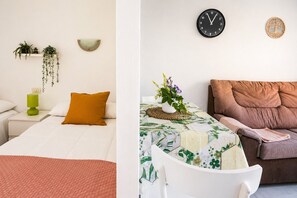 A room with a bed, a nightstand, a green lamp, a wall-mounted clock, and a brown sofa. - Modern Studio with Pool, Puerto de La Cruz (Puerto de la Cruz)