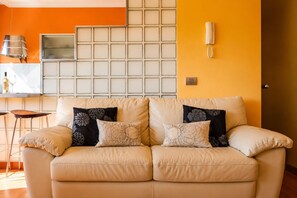 A beige sofa with floral cushions, a wall-mounted telephone, and a tiled backsplash.