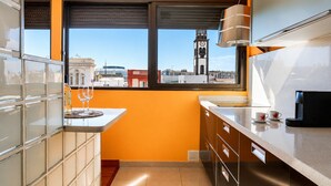 A kitchen with a window view, a coffee machine, and a wine glass on the counter.