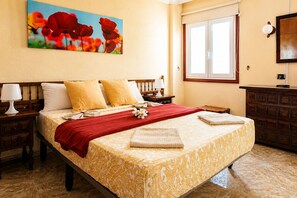 Une chambre d’hôtel bien rangée, avec un lit, des tables de chevet, une commode, une fenêtre et un tableau au mur.