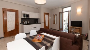 Un appartement moderne comprenant un coin repas, une cuisine, un salon et un balcon équipé d’un téléviseur.