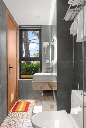 Bathroom features a large window, sink, and separate shower area with glass enclosure.