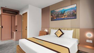A hotel room with a large bed, a painting on the wall, a bedside table, and a wardrobe.
