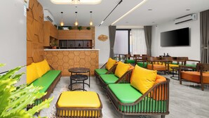 A modern living room with a sofa set, a coffee table, a TV, and a kitchen area with a wooden wall and a ceiling light.
