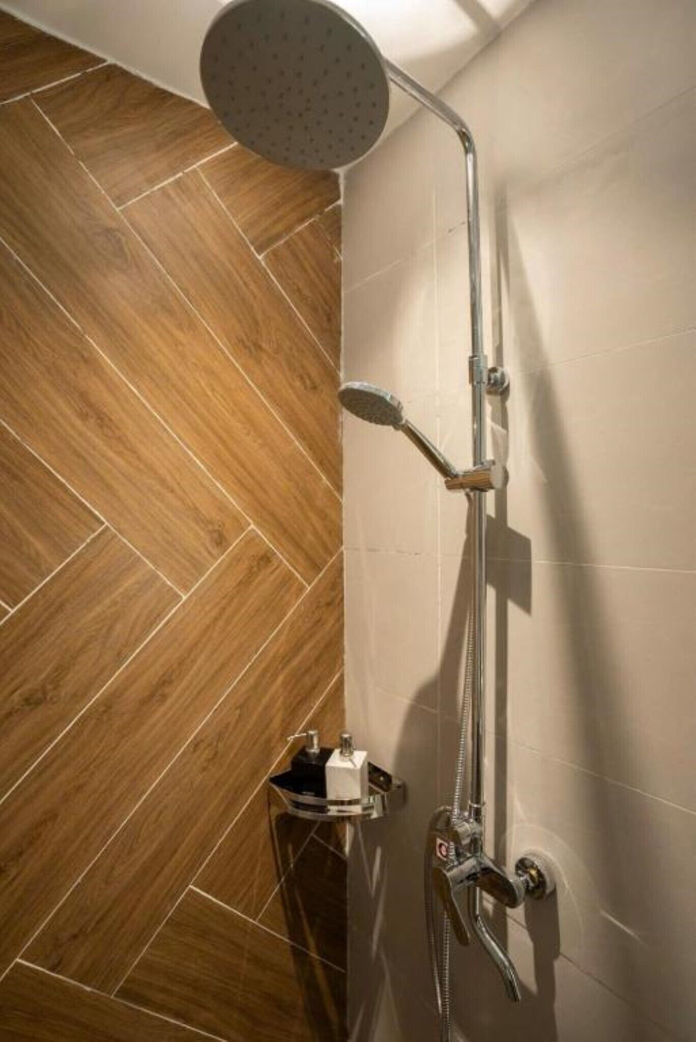 A shower with a handheld showerhead and a wall-mounted faucet.