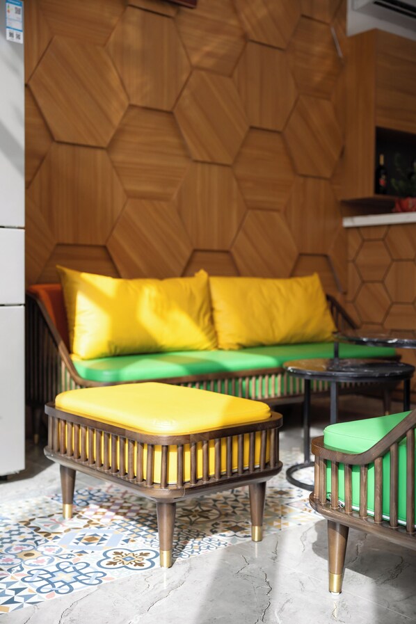 A room with a wooden hexagonal wall, a green and yellow sofa, and a patterned floor. - Khue Le Bleu Villa- Flamingo Hai Tien (Hoang Tien)